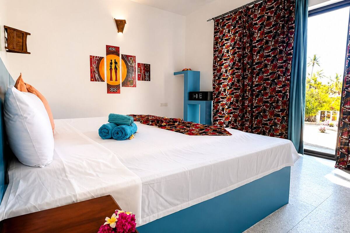 Une chambre d’hôtel avec un lit, un mur d’accent bleu, une œuvre d’art accrochée au mur et une vue par la fenêtre.