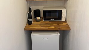 Una kitchenette compacta con microondas, un refrigerador pequeño y una encimera de madera.