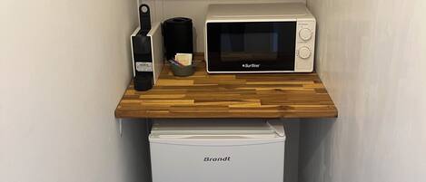 A compact kitchenette with a microwave, a small refrigerator, and a wooden countertop.