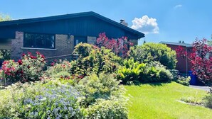 Une maison dotée d’un jardin bien entretenu, agrémenté de diverses fleurs et arbustes aux couleurs vives.