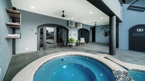 Ein moderner Poolbereich im Innenbereich mit einem von Glas umgebenen Pool, Sitzbereichen und einer Rezeption.
