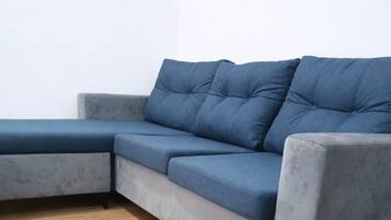 Un sofá seccional gris con chaise, piso de madera y pared blanca lisa.