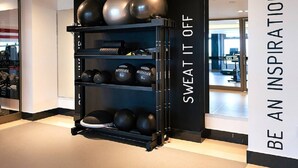Une salle de sport avec un support mural contenant différents ballons d’exercice et des poids.