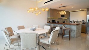 Une cuisine moderne dotée d’un îlot central, d’appareils électroménagers en acier inoxydable et d’un luminaire suspendu.