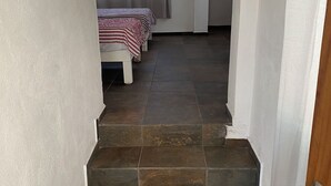 A staircase leading to a bedroom with a bed and a window with curtains.