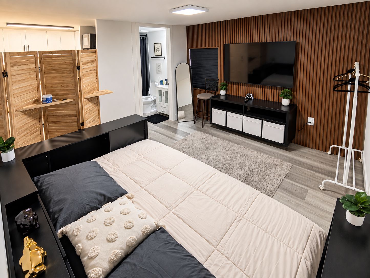 Ein modernes Schlafzimmer mit einem großen Bett, einem Fernseher und einem Holzschrank.