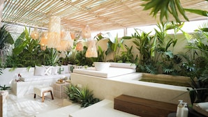 A modern, well-lit indoor space with a bamboo ceiling, white furniture, and lush green plants. - Casa Palma🌴 (Marrakech)