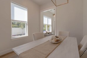 Ein modernes, minimalistisches Zimmer mit einem großen Fenster, einem Esstisch mit Platzsetzer und einer hängenden Leuchte.