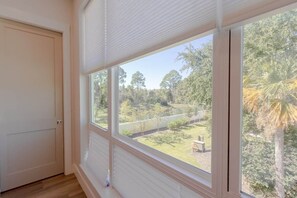 Ein Zimmer mit großem Fenster, einer Tür und Holzboden.