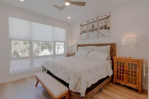 Ein Schlafzimmer mit Bett, Bank, Fenster, Deckenventilator und Holzschrank.
