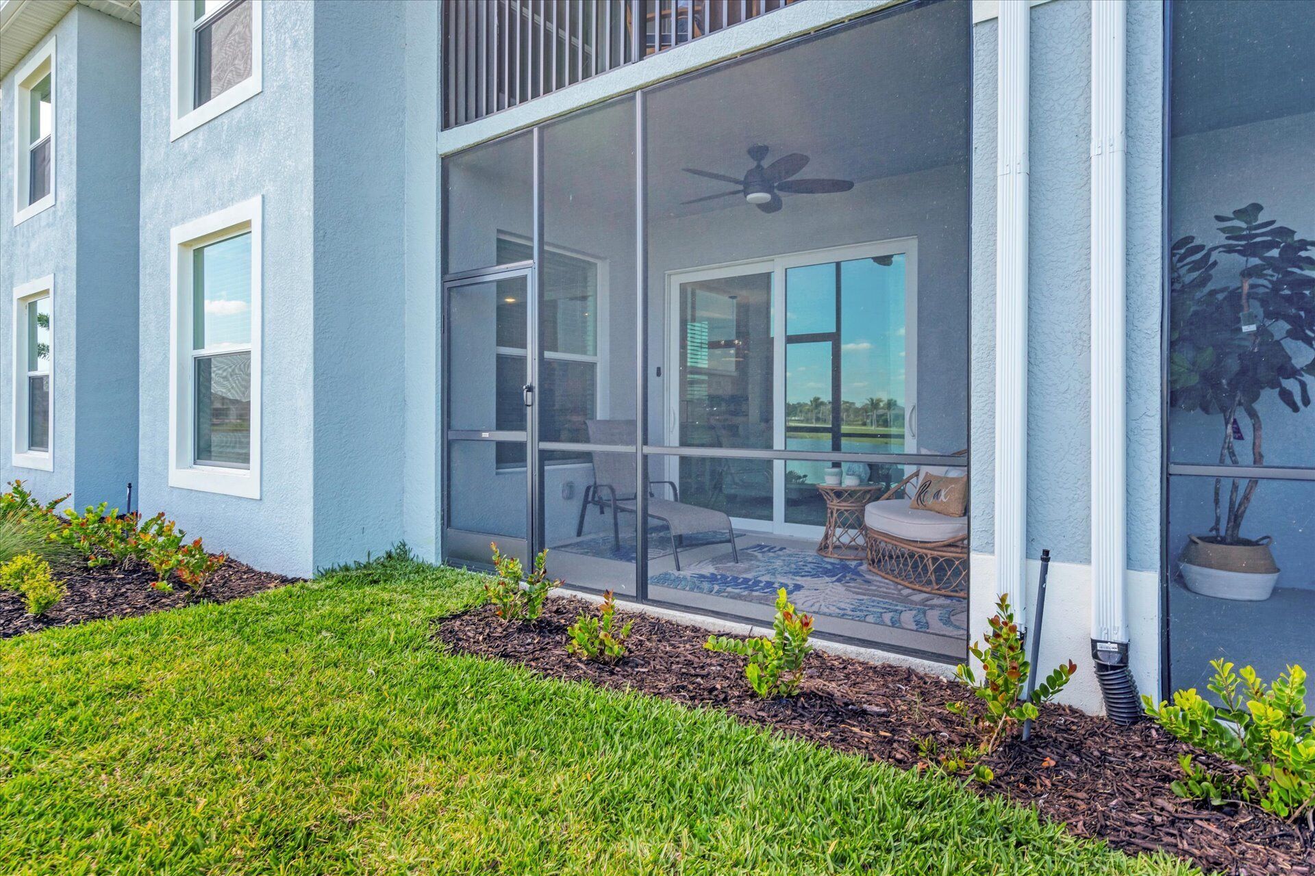 A modern house with a large sliding glass door leading to a patio area with outdoor furniture.