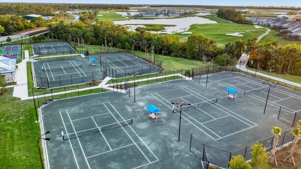 Un complexe sportif proposant diverses activités, avec des courts de tennis, un parcours de golf et des immeubles résidentiels.