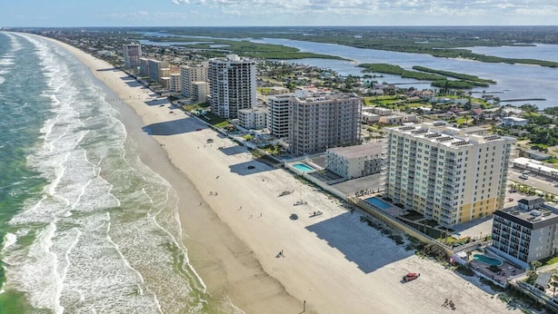A coastal hotel with multiple high-rise buildings, a beach, and a marina. - A Wave From it All Oceanfront Pool Condo (Daytona Beach Shores)