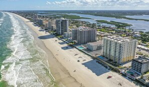 A coastal hotel with multiple high-rise buildings, a beach, and a marina. - A Wave From it All Oceanfront Pool Condo (Daytona Beach Shores)