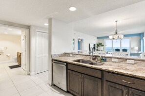 A modern kitchen with a marble countertop, stainless steel sink, and built-in dishwasher.