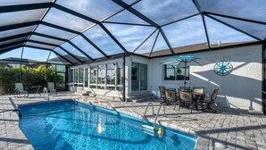 A covered swimming pool with a glass ceiling, adjacent patio area with outdoor furniture, and a wall-mounted compass. - Aqc15826 (Port Charlotte)