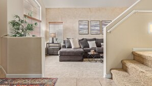 A modern living room with a sectional sofa, a small side table, and a staircase. - Family Fun in Ahwatukee Phoenix (Phoenix)