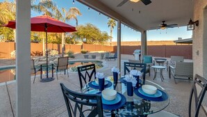Eine Terrasse im Freien mit Essplätzen, einem Deckenventilator und Blick auf die Wüstenlandschaft.