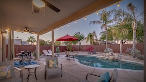 Eine Außenpatio mit Pool, Sitzbereich und Lichterkette.