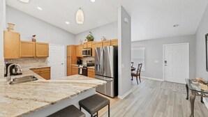 Une cuisine moderne avec des meubles en bois, un réfrigérateur en acier inoxydable et un plan de travail en marbre.
