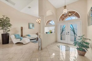 A spacious living area with a white sofa, a large potted plant, and a decorative sculpture. - Aa15432 South Gulf Cove 4 (Port Charlotte)