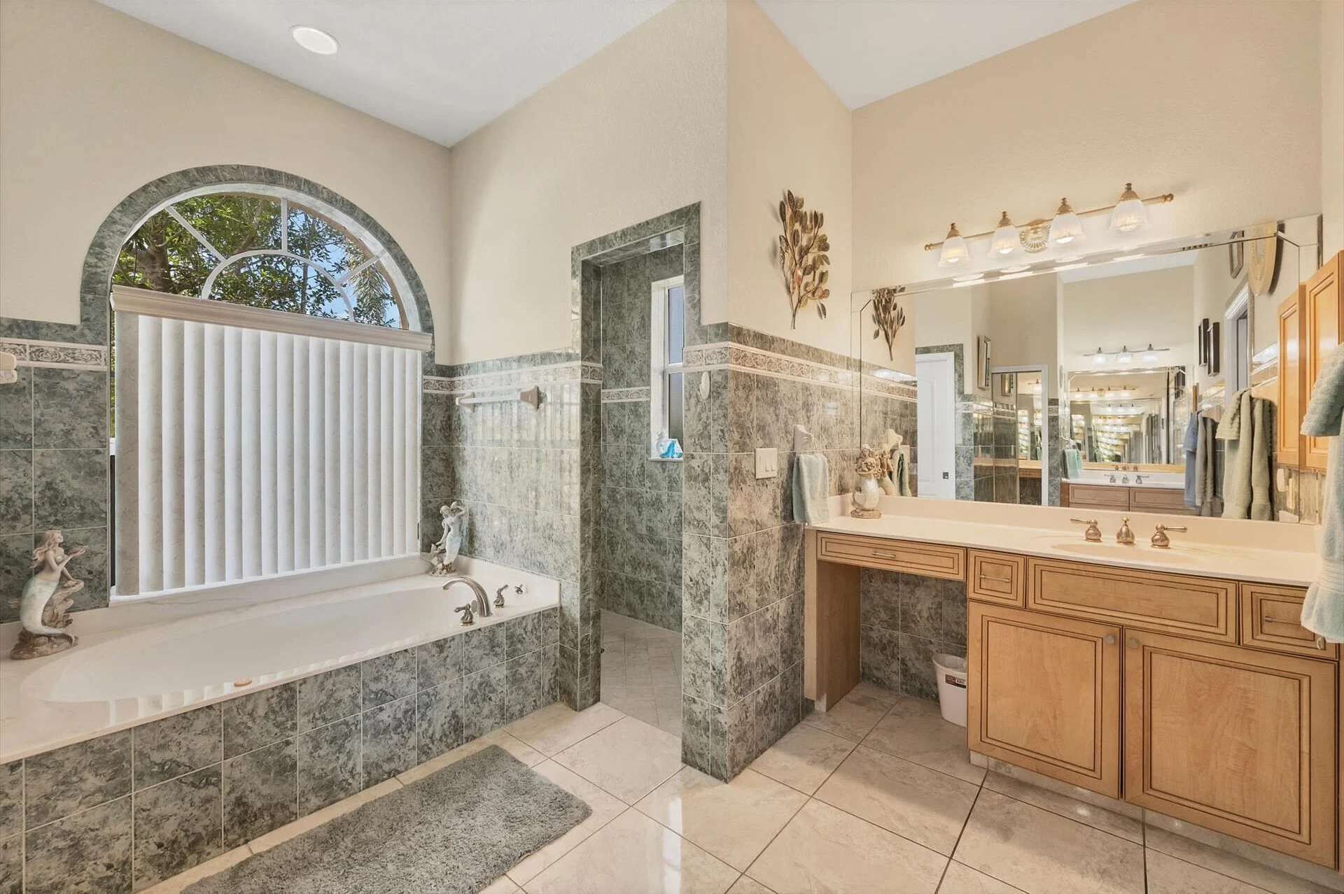 A bathroom with a bathtub, a large mirror, and marble tiles.