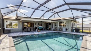 A covered outdoor swimming pool with a patio area, lounge chairs, and a bar. - Blc200 (Punta Gorda)