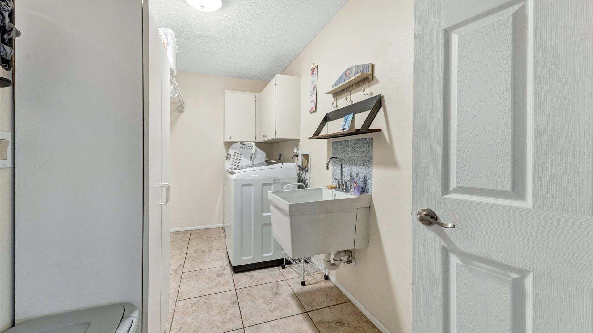 A compact kitchen with a washing machine, a sink, and a small countertop.
