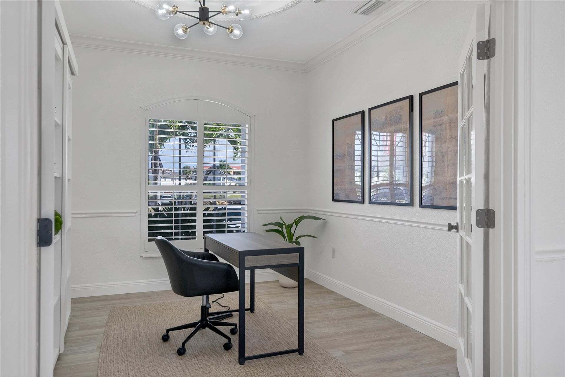 A room with a desk, chair, and a window with blinds.