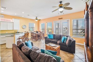 A spacious living area with a dark brown sofa, a coffee table, and a dining area with wooden chairs and a table. - Villa Laguna - Pet Friendly! Beach Gear Credit Included! (Port Aransas)