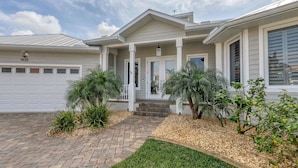 A two-story house with a covered porch, a garage, and a well-maintained front yard with shrubs and a brick pathway. - Rvc1435 (Punta Gorda)
