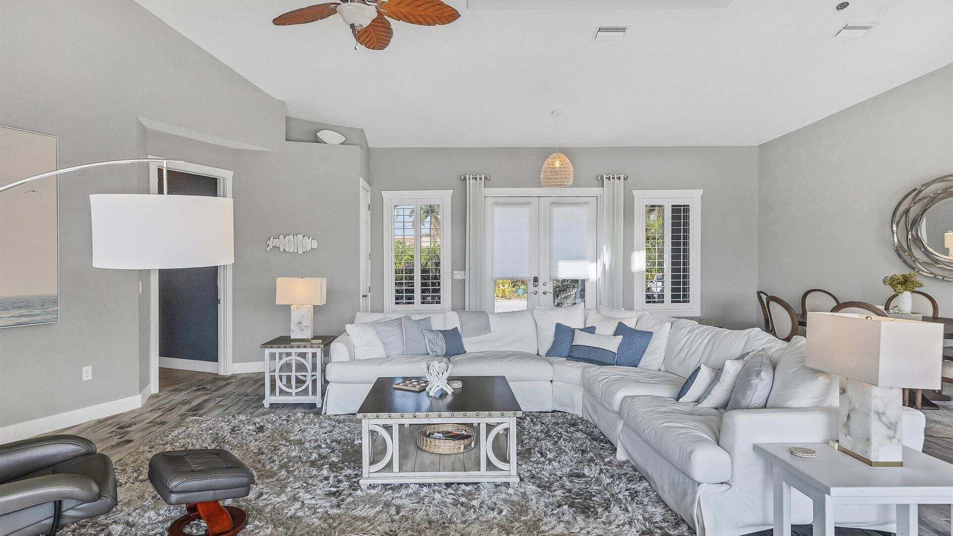 A living room with a white sofa, a coffee table, a floor lamp, and a ceiling fan.