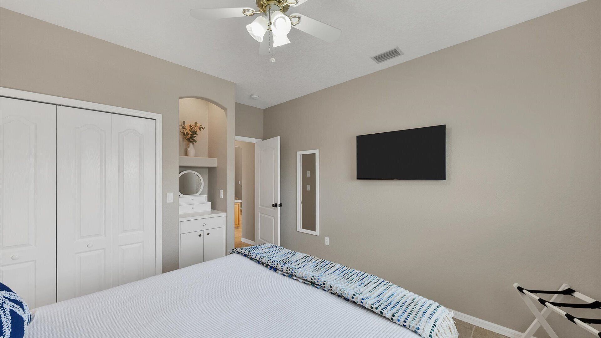Una camera da letto con un letto, una ventola a soffitto, una TV e un armadio.