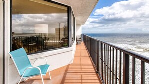 Un balcone con vista sull'oceano, una sedia e una ringhiera.