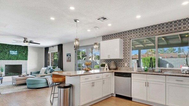 Una cocina moderna con armarios blancos, un ventanal grande y una pared verde.