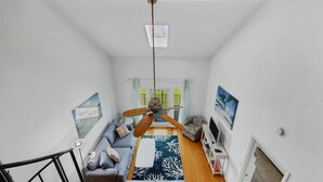 A narrow hallway with a ceiling fan, a sofa with cushions, a patterned rug, and a television on a stand. - Port Charlotte Private Waterfront Condo Wa4410-317 (Port Charlotte)