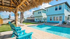 A backyard with a swimming pool, a covered patio, and a two-story house. - Ruby Tuesday (Port Aransas)