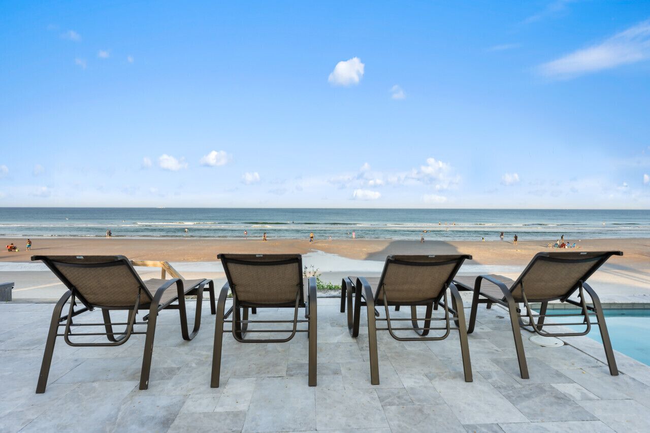 Zona de piscina con sillones de descanso frente a la playa.