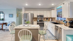 A modern kitchen with white cabinets, stainless steel appliances, and a granite countertop. - Under The Sea Pool and Hot Tub (Port Orange)