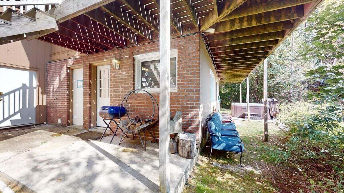 A covered patio area with a barbecue grill, a blue chair, and a wooden bench.