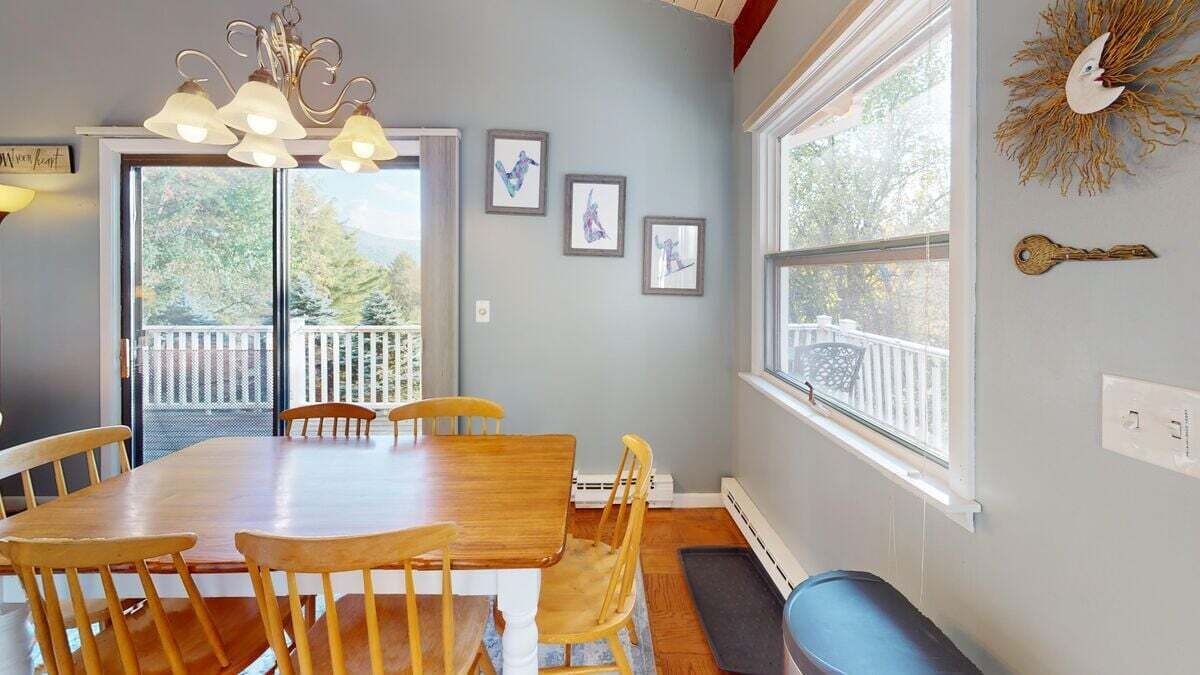 A dining area with a wooden table and chairs, a chandelier, and framed artwork on the wall.