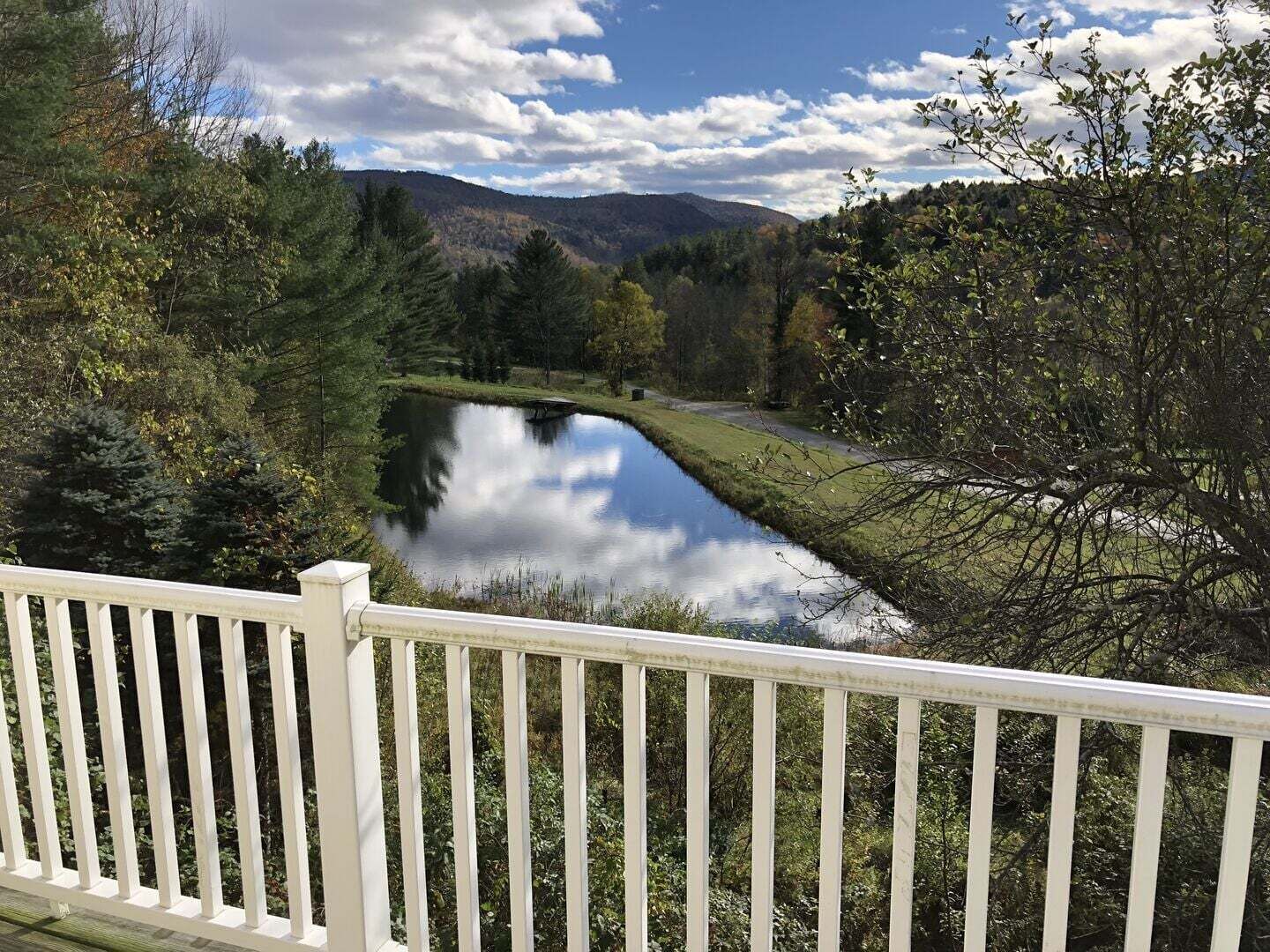 A serene landscape with a lake, surrounded by trees and hills.