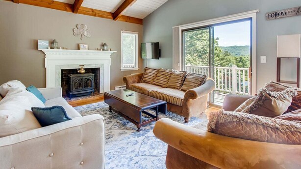 Una sala de estar acogedora con chimenea, sofá, mesa de centro y un balcón con vistas.