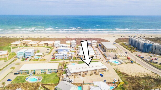 An aerial view of a coastal hotel with multiple buildings, a swimming pool, and a beach in the background. - Sunrise Villas 101 - Boardwalk TO THE Beach! (Port Aransas)
