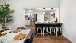 Een moderne keuken met witte kasten, roestvrijstalen apparatuur en een centraal eiland met barstoelen.