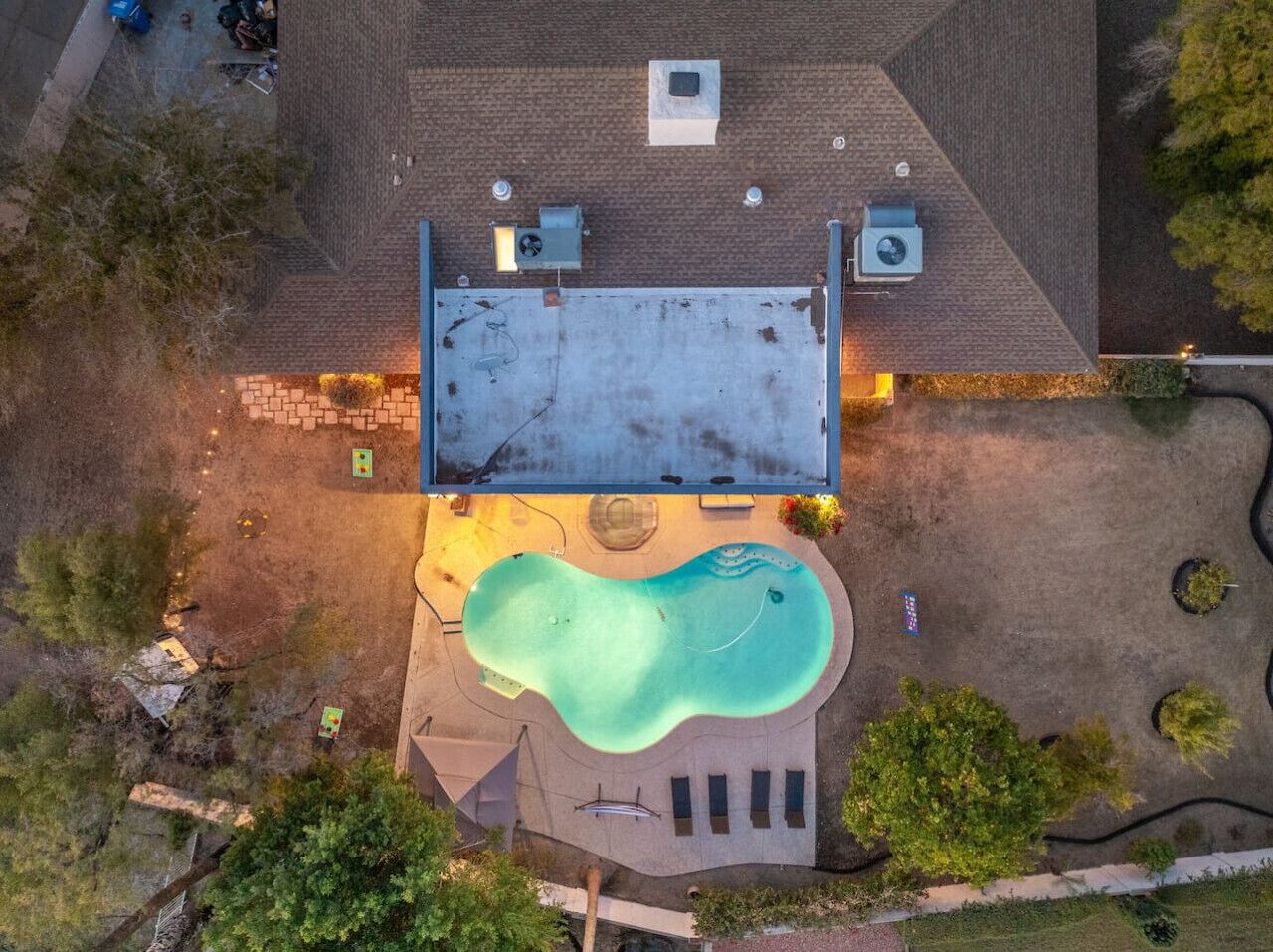 Vue aérienne d’une propriété résidentielle dotée d’une piscine, d’un patio couvert et d’un garage.