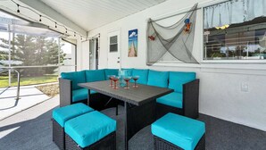 Ein Außenbereich mit einer Terrasse, einem blauen Sofa, einem Tisch mit Getränken und einer Netzdekoration.
