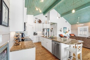 A modern kitchen with white cabinets, a granite countertop, and a dishwasher. - Sandy Craic - Elevator! Beach Gear Credit Included (Port Aransas)
