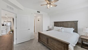 A bedroom with a wooden bed, white bedding, a nightstand, and a ceiling fan. - Hlb14131-828 (Punta Gorda)