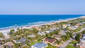A coastal residential area with houses, a beach, and a clear sky. - Sandcastle Harbor Pool & Firepit Steps to the Beach! (Ponce Inlet)